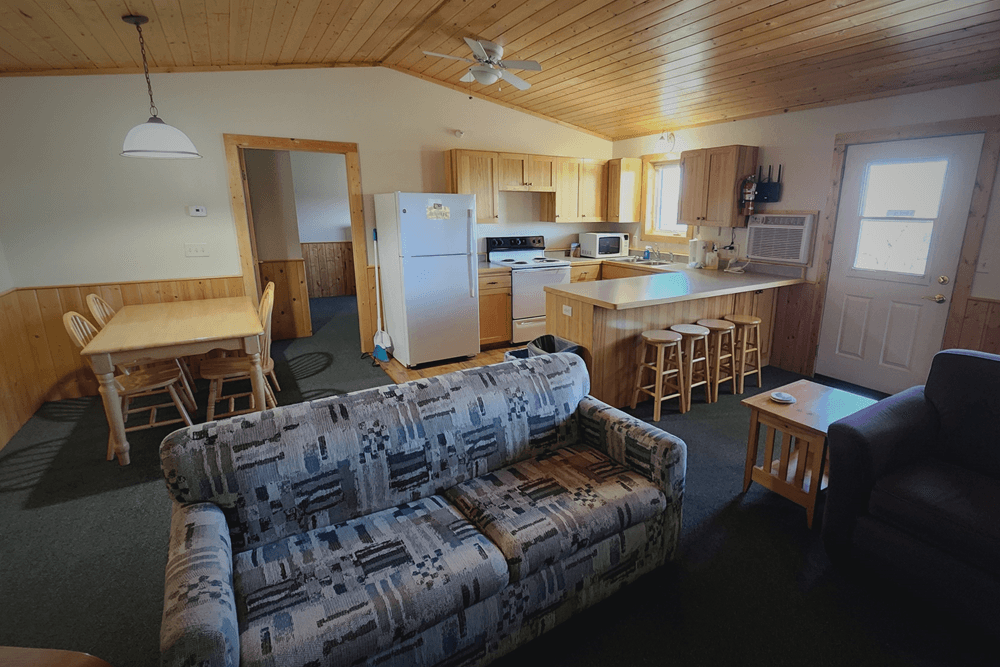 Cream walls, pine ceiling and furniture, in cabin style with couch and kitchen