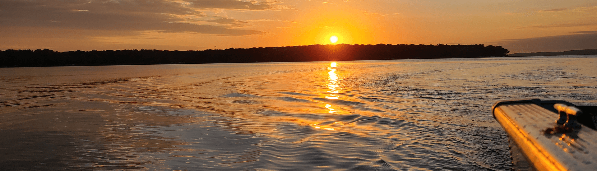 Sunset on water with corner of boat in photo