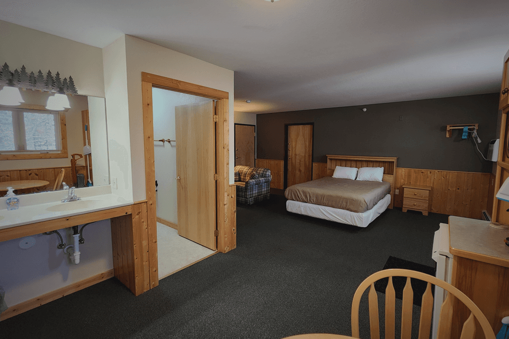 Bedroom with Bed with dark coverlet, door to bath and exterior bath sink